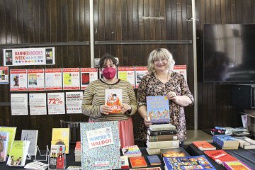 Janis Winn and colleague hold up books during Banned Books Week 2025 Event.
